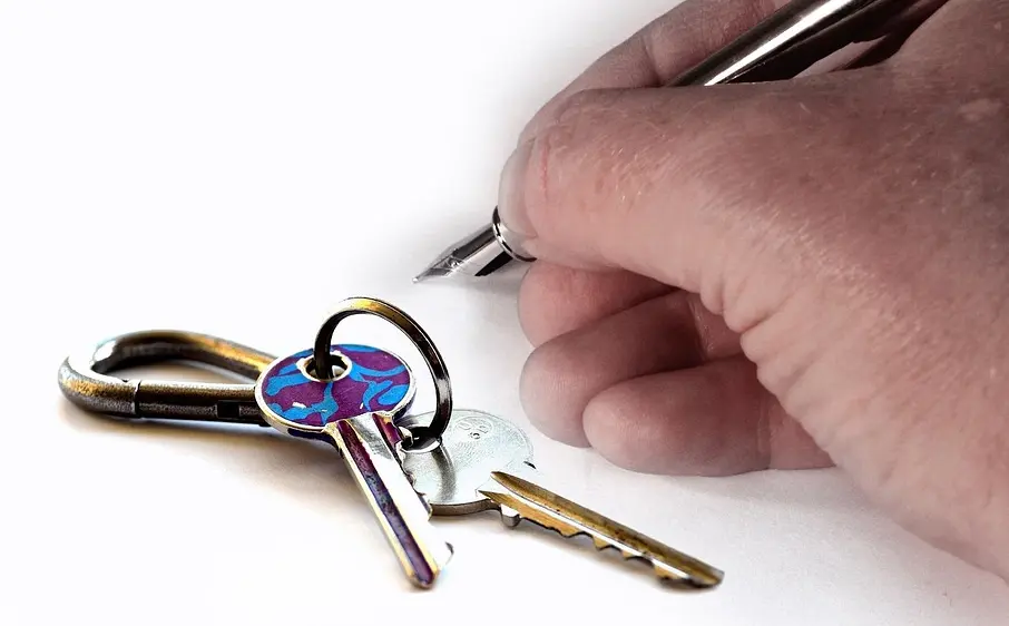 Keys next to hand holding pen
