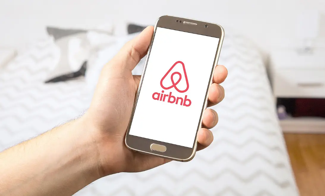 Hand holding cellphone with airbnb logo