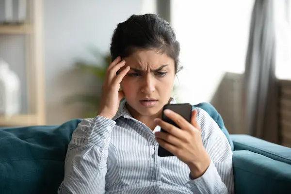A woman looking at a cell phone in distress