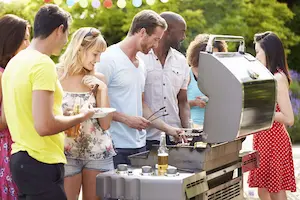 People standing around a BBQ grill