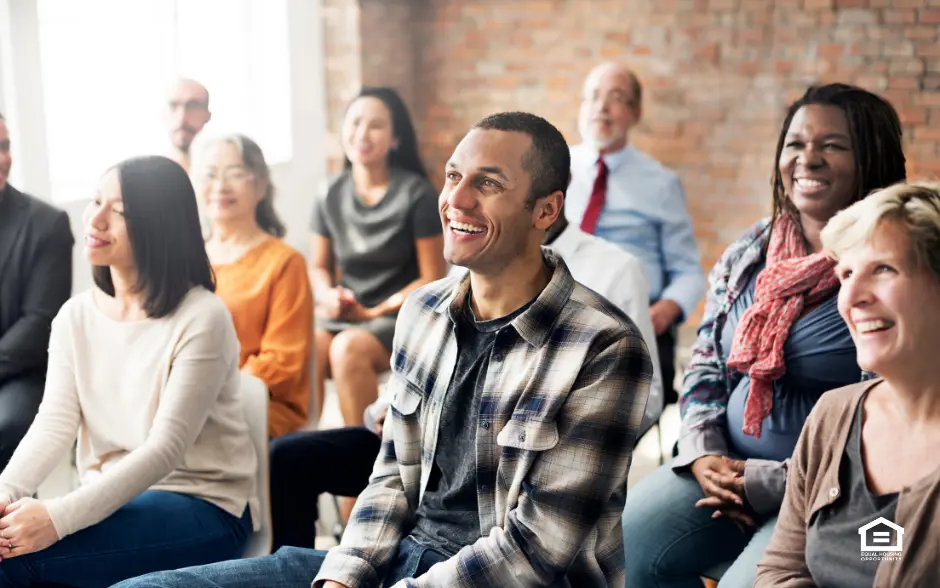 Audience members at a real estate conference smiling.