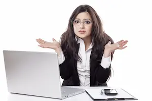 A woman sitting at a desk with a laptop looking confused