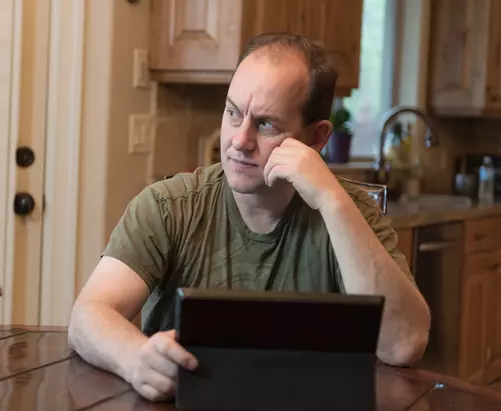 man thinking at laptop