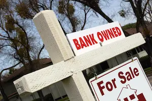 A For Sale sign on a post in front of a house