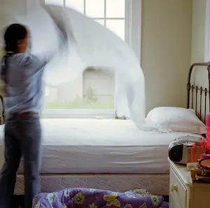 A woman changing sheets on a bed