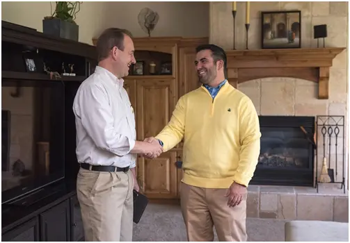 two men shaking hands in a living room