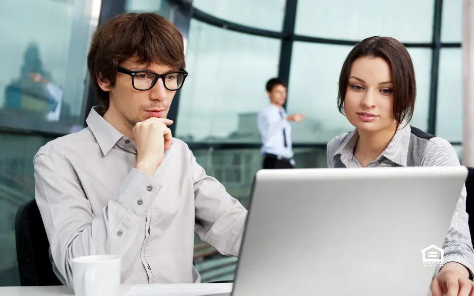 Man and woman looking at laptop forecasting real estate market