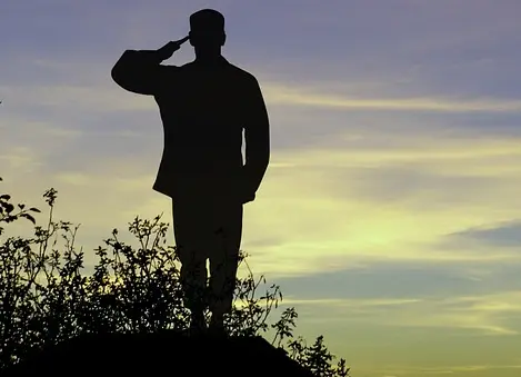 Man saluting on a hill at sunset