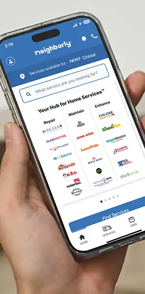 Close-up of hand holding smartphone with Neighborly App 'Your Hub for Home Services' displayed on screen.