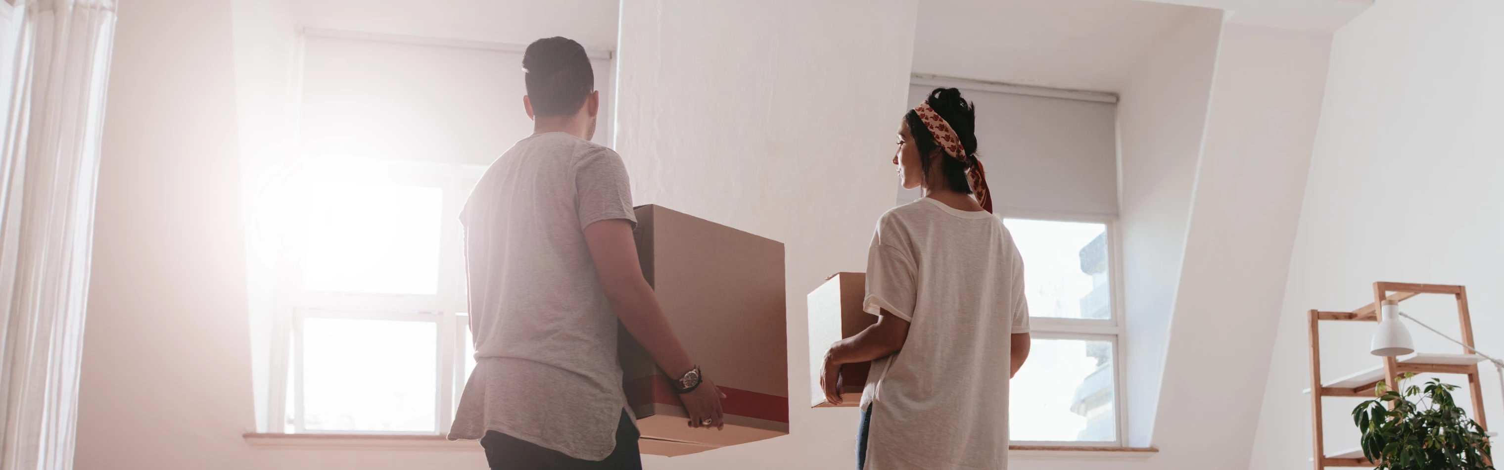 Man and woman moving boxes in brightly lit interior.