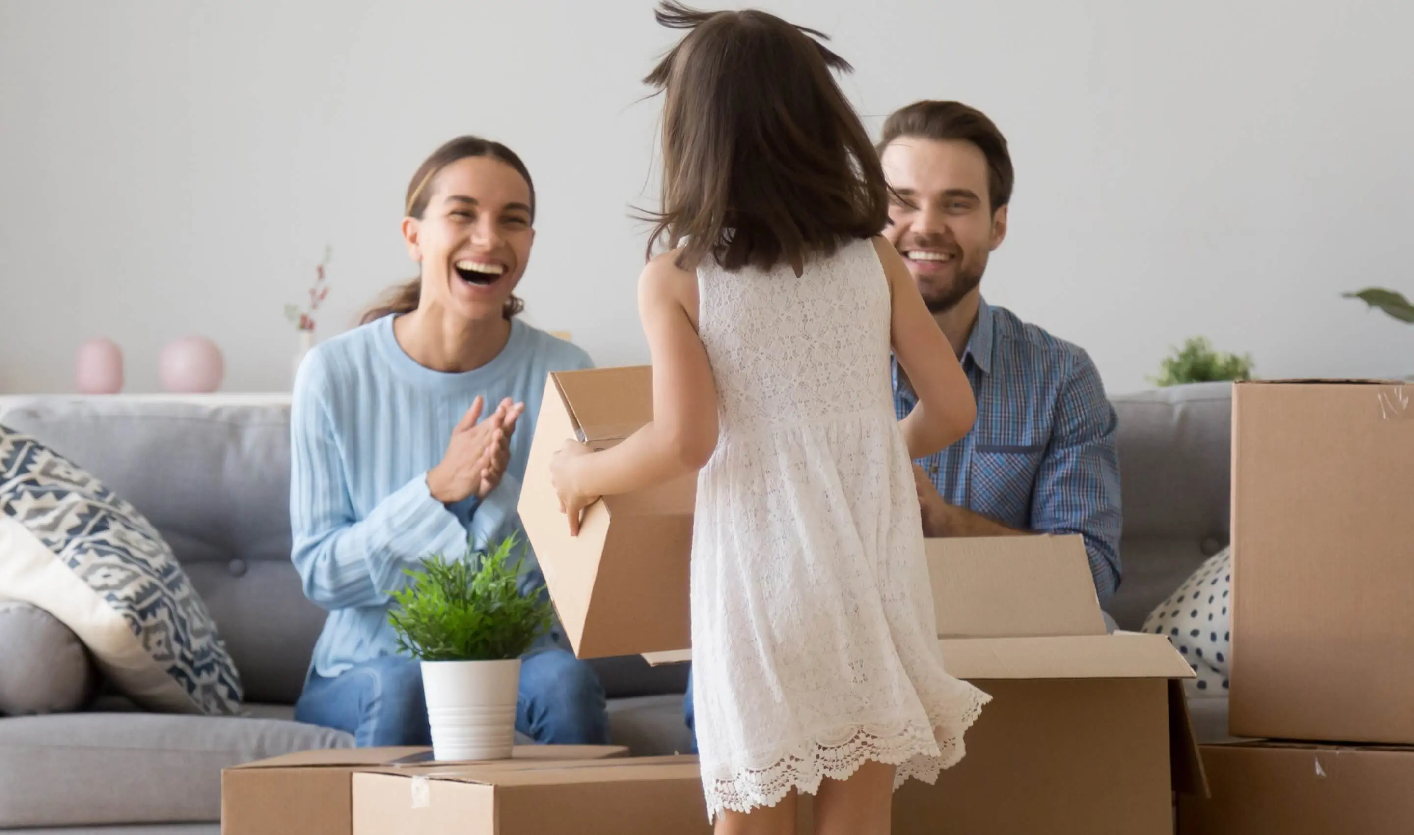 Family smiling and having fun unpacking boxes in living room.