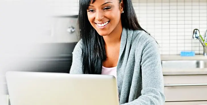 Woman Smiling and Working on Laptop